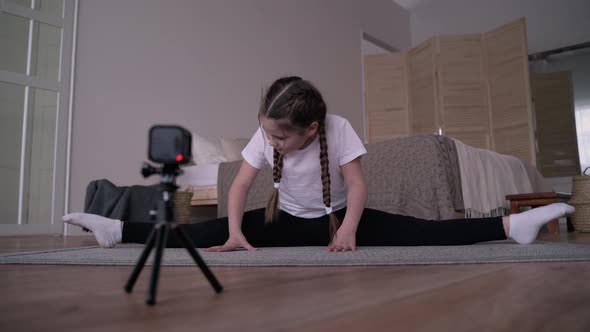 Girl Child Broadcasts an Online Course and Writes a Vlog About Gymnastics at Home alt