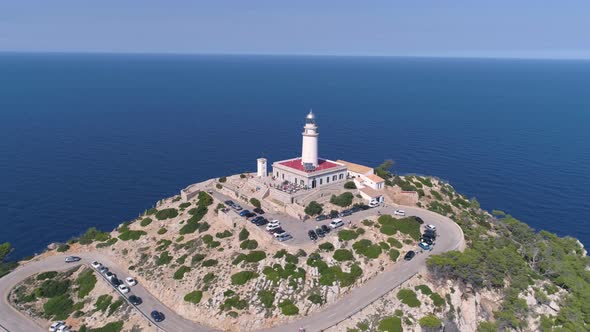 Lighthouse on rocky seashore with curved road alt