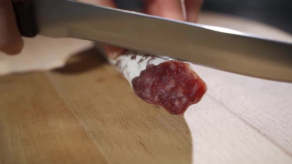 An Experienced Chef in a Professional Kitchen Cuts the Seasoned Italian Salami Sausage Is Cut with a alt