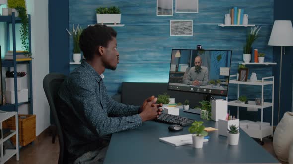 Remote Black Worker Using Internet Web Online Communication to Talk with His Boss alt