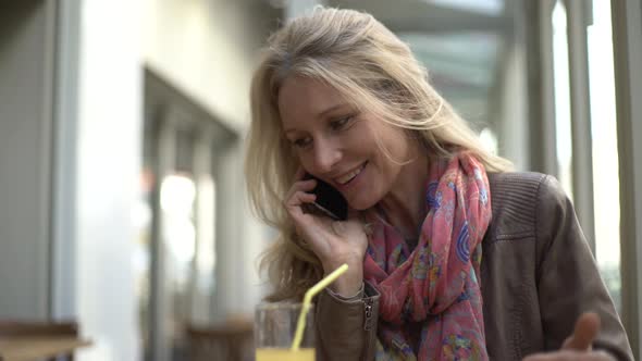 Woman talking smart phone while drinking juice