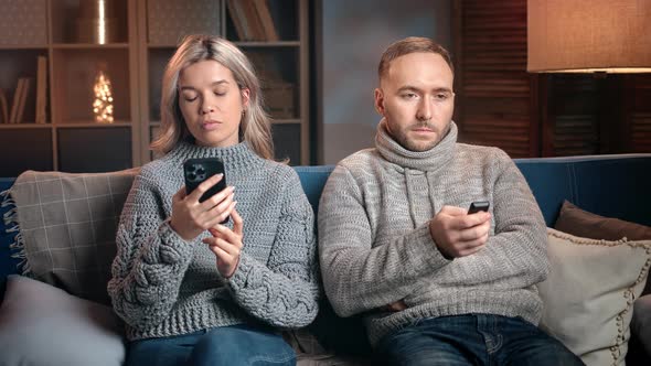 Indifferent Married Couple Sitting Couch Chatting Smartphone Watching TV Separated at Evening Home alt