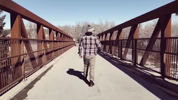 Man Walking Across Bridge