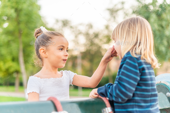 A little sister grabbing nose of little brother at park