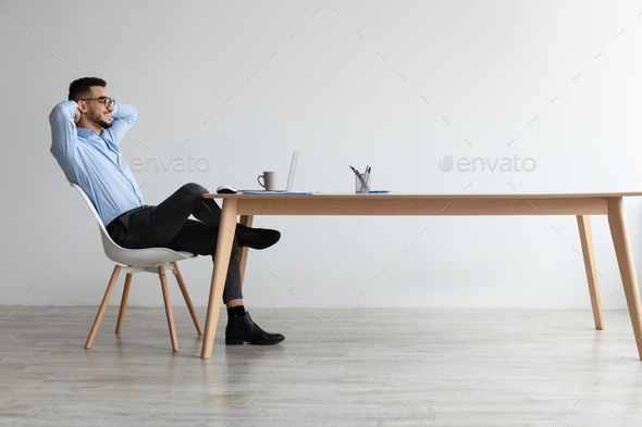 Smiling Arab man leaning back sitting at desk