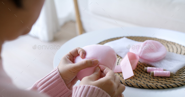 Close-up hand asia woman help make craft pink single fill up bra cup insert for post mastectomy