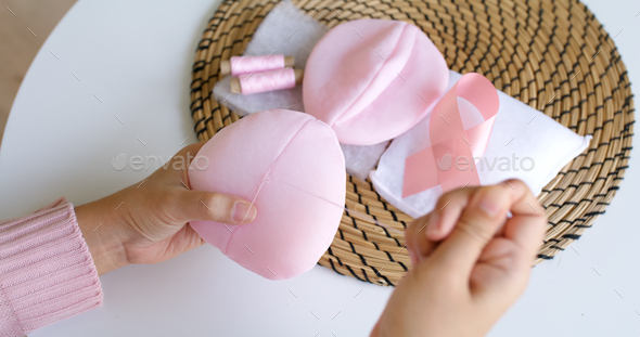 Close-up hand asia woman help make craft pink single fill up bra cup insert for post mastectomy
