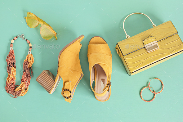 Flat lay with woman fashion accessories in yellow color over