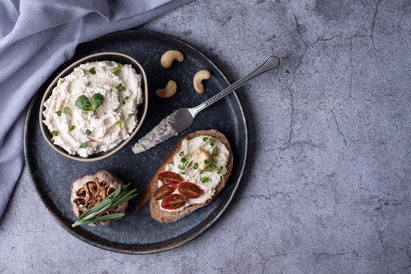 Bowl with fermented nut spread, slice of bread with cashew cheese.