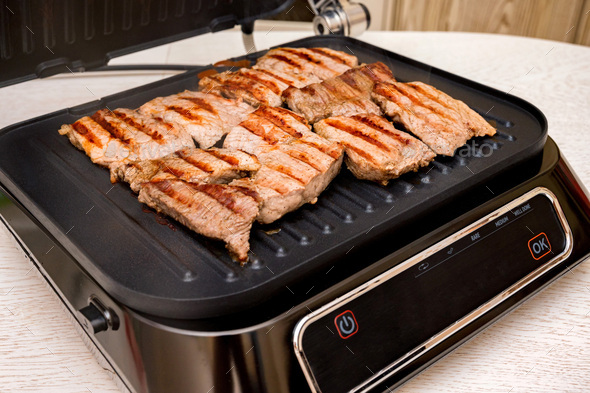The process of cooking pork meat on electric grill close-up - Stock Photo - Images