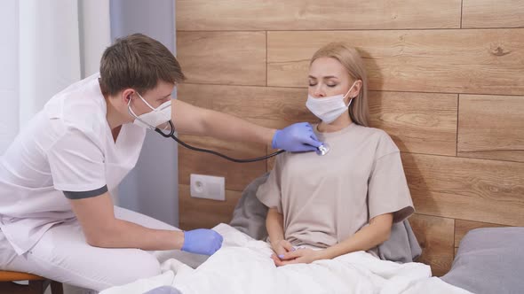 Male Doctor is Going to Examine Sick Patient Lying on Bed