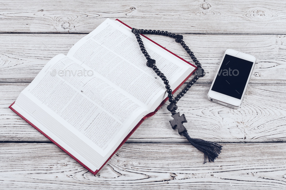 Holy Bible and smartphone with black coffee cup on wooden background