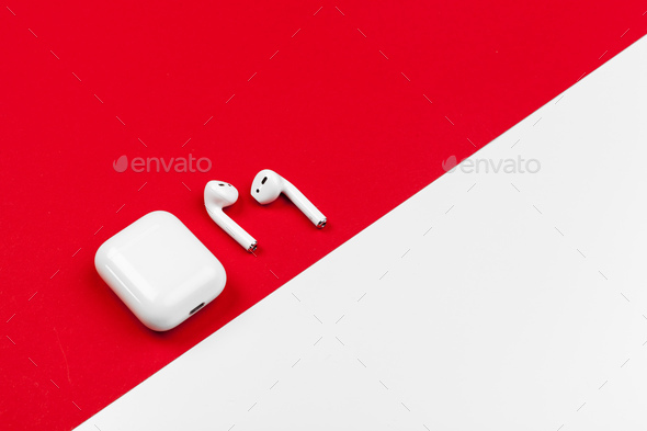 White modern wireless earphones with box on bright red background