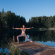 Young woman on wooden pier above forest lake scenery, folds her arms in a namaste gesture. Woman - PhotoDune Item for Sale