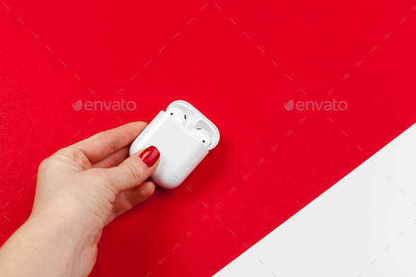 White modern wireless earphones with box on bright red background
