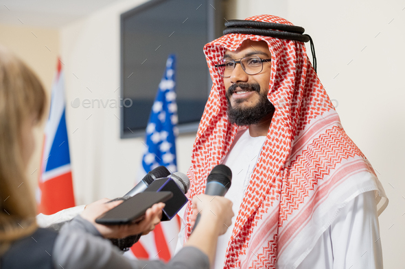 Young Arabian businessman in national clothes giving interview to journalists