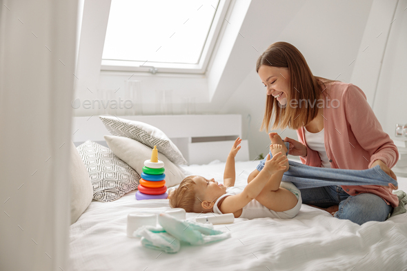Happy mom with her baby boy during changing the clothes