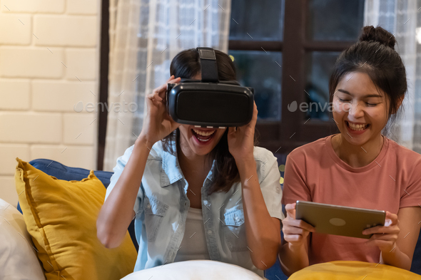 konvertering Almindelig pakistanske Happy asian lesbian play virtual reality goggle with tablet together at  sofa in living room at home Stock Photo by Weedezign_photo
