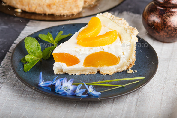 A piece of peach cheesecake on a blue ceramic plate with blue flowers and a cup of coffee