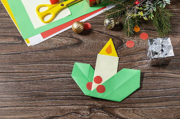 Christmas greeting card gift origami candle on wooden table.