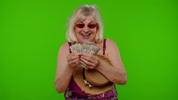 Senior Woman Traveler Tourist Takes Money From Hat Counting Bunch of Dollars Cash for Summer Trip alt
