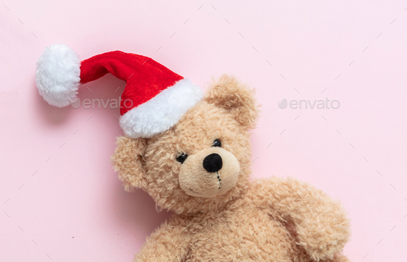 Christmas present. Teddy bear wearing Santa hat on pastel pink background, Holiday greeting card.