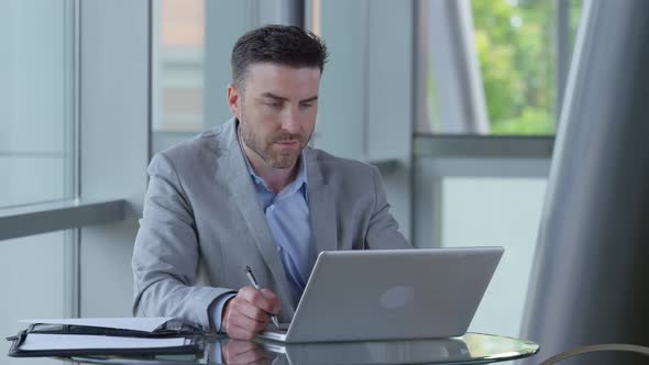Young businessman using laptop computer in office lobby