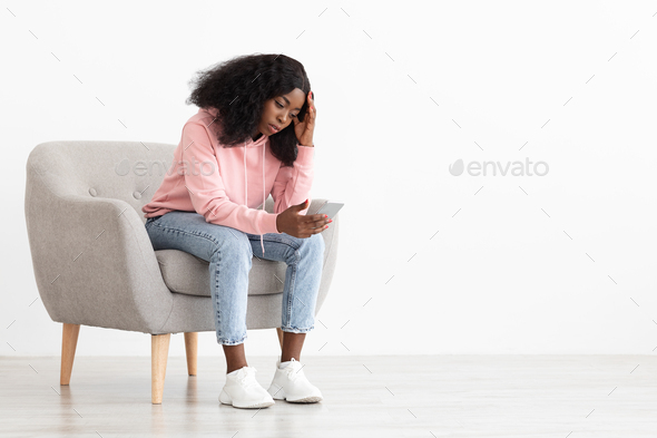 Frustrated black woman looking at smartphone screen