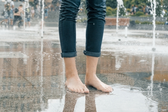 Legs of young girl in wet jeans with summer city fountain