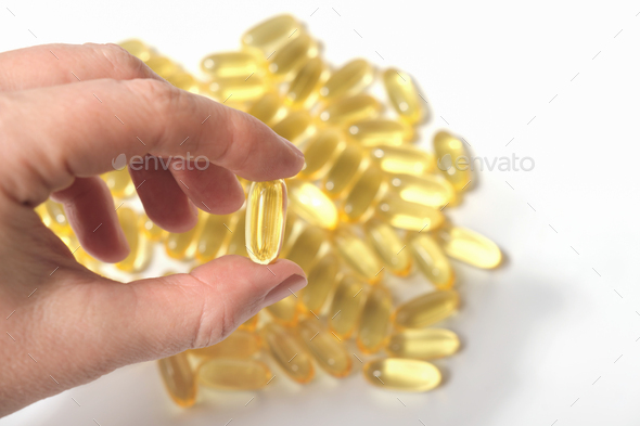 hand holding a capsule of cod liver oil. healthy living supplement for brain boost