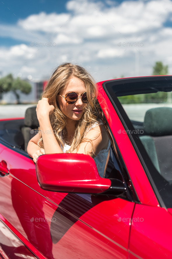 Beautiful blonde girl in a convertible red car. Sunny day Stock