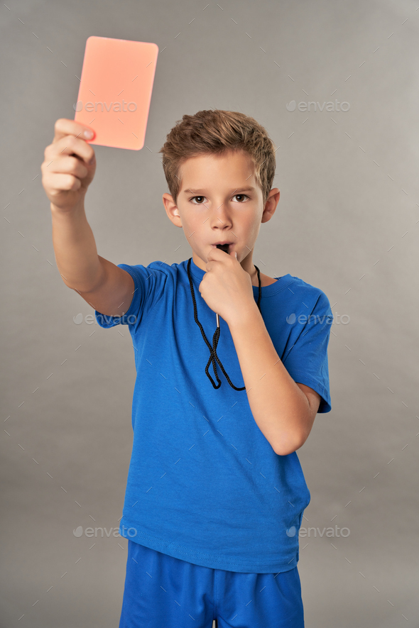 Cute boy referee holding red card and whistling in whistle