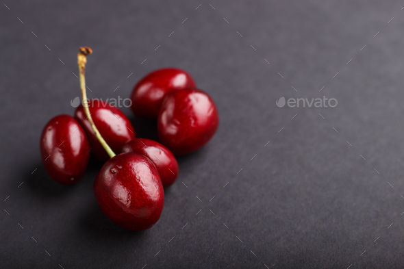 Ugly weird red sweet cherry on black background. side view. food concept.