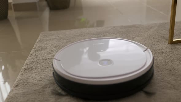 White Round Robot Vacuum Cleaner Cleaning Carpet Floor alt