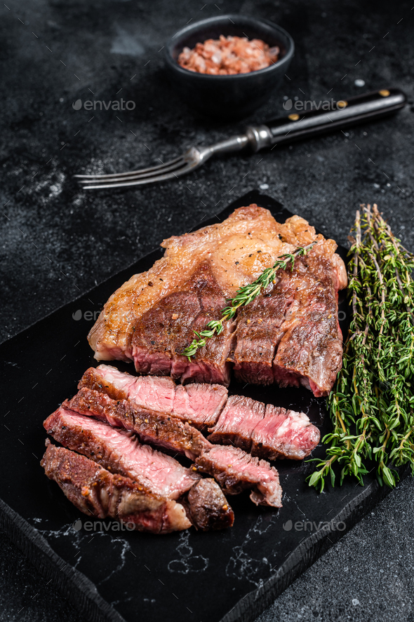 Roasted bbq Chuck Roll beef steaks with herbs. Black background. Top