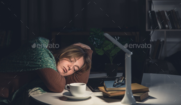 Tired young woman at the workplace wants to sleep late at night.