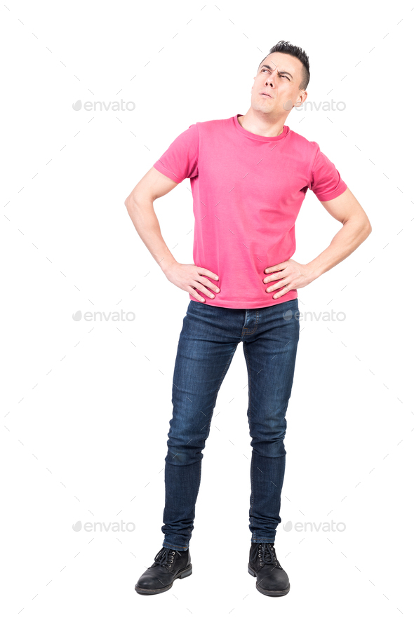 Thoughtful man standing with hands on waist and looking away - Stock Photo - Images