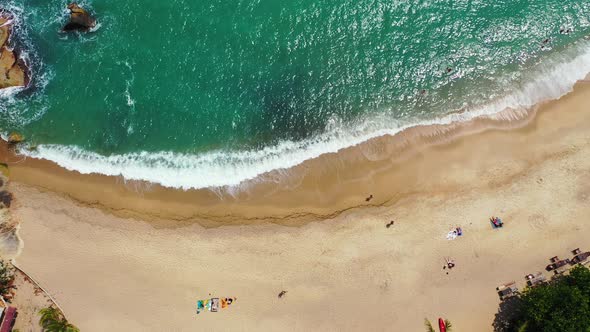 Foamy waves rolling over the golden sand coast. Aerial background of a tropical sea and surf waves. alt