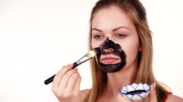 Girl Applying Black Mask to Face