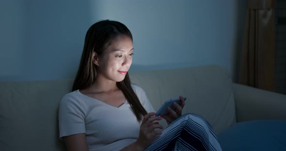 Woman watch on cellphone at home in the evening alt