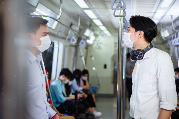 Asian man wearing mask talking with friend in subway