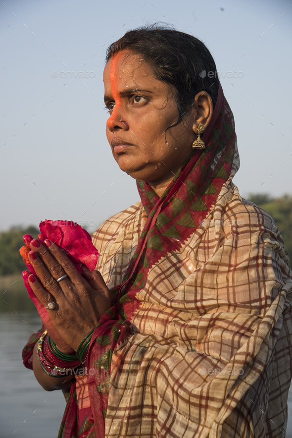 Traditionally dressed Indian woman pray into the river on Chhat Puja ...