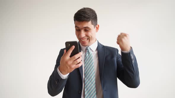 Happy Male Office Worker in Formal Clothes Uses Mobile Phone Rejoices in Victory alt