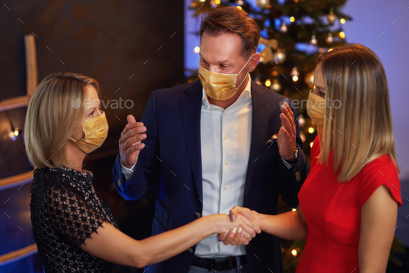 Business friends celebrating christmas party wearing masks