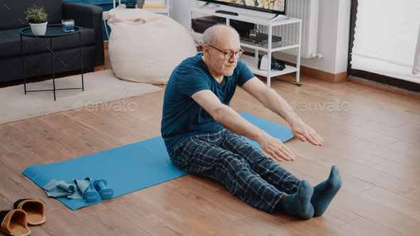 Elder adult sitting on yoga mat and pulling resistance band Stock Photo by  DC_Studio