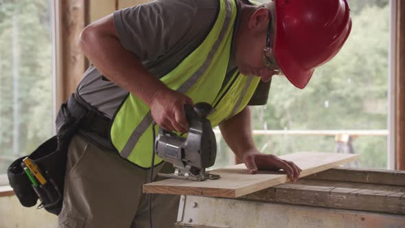Construction worker cutting wood with jigsaw