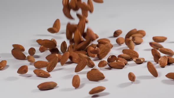 Almonds falling onto a white surface in slow motion alt