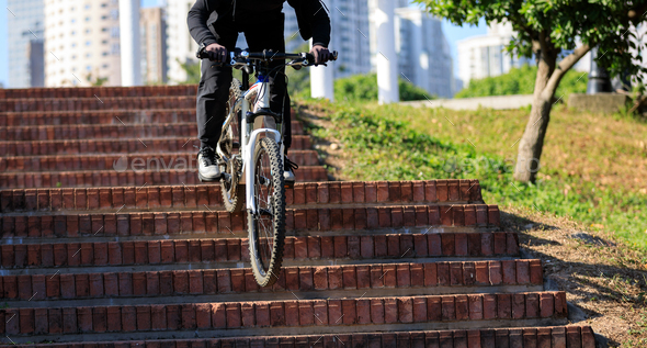 Woman free rider riding bike going down city stairs