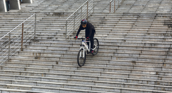Woman free rider riding bike climbing up city stairs