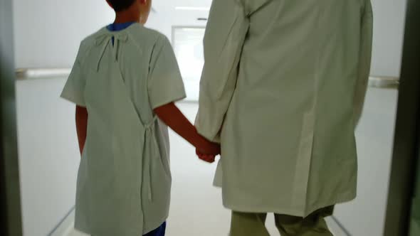 Doctor walking with patient in hospital corridor alt